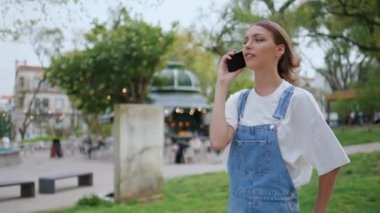 Gençler şehir parkında yürürken telefonla konuşmaktan hoşlanırlar. Yeşil caddede cep telefonuyla konuşan gülümseyen kadın. Kaygısız kız akıllı telefonla konuşuyor. Şehirde tek başına dolaşıyor. Mobil iletişim konsepti