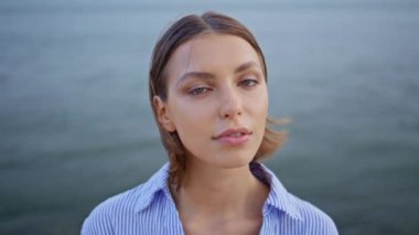 Deniz kenarında duran portre modeli kendini sakin hissediyor. Rahatlamış esmer doğa huzurunun ve huzurlu çevrenin tadını çıkarıyor. Güzel bir bayan çizgili gömlek giyerek okyanus yüzeyine bakıyor. Sakin kadın ışıldayan güzellik 