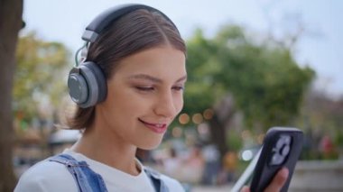 Kulaklıklı kadın Sunny Sokağı 'nın kapanışında akıllı telefon ekranına bakıyor. Tasasız ergen cep telefonu uygulamasına bakıyor kablosuz kulaklıkla müzik dinliyor. Cep telefonuyla kameraya gülümseyen neşeli kız..
