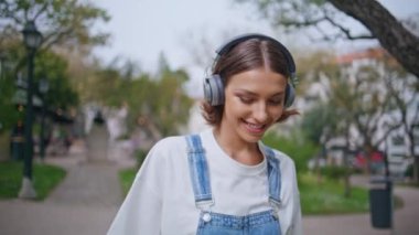 Kulaklık takan kadın doğa güzelliğine yakından bakıyor. Telsiz kulaklıkla müzik dinleyen mutlu bir genç. Rahat, modaya uygun esmer, şehirde gezen, kulaklıkla sesin tadını çıkaran..