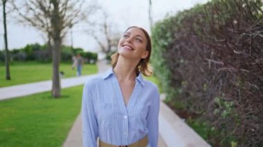 Mutlu manken parkı, yakından gülümsüyor. Neşeli esmer kadın yeşil bitkilerle çevrili yolda rahatça dolaşmaktan zevk alıyor. Neşeli genç kız bahçe yolunda zıplıyor kaygısızca.