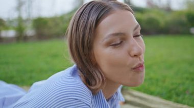 Green Park 'ta piknik yapan bir kızı yemek. Güzel doğada üzüm çiğneyen tatmin olmuş bir kadının portresi. Kaygısız esmer, gülümseyen taze sağlıklı atıştırmalıkları tadıyor canlı çimenlerin üzerinde battaniyenin üzerinde yatıyor.