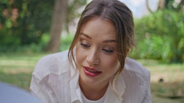 Güzel bir öğrenci yeşil çimen parkında uzanan kitabı yakından izlemeyi sever. Genç bir kadın, güneşli doğayla ilgili sayfaları çeviriyor. Tasasız kız bahçedeki yeşillikte eğitim edebiyatıyla rahatlıyor..