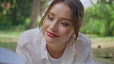 Gülümseyen kadın bahçede kitap okuyor. Huzurlu ve mutlu bir şekilde yakın çekim yapıyor. Genç kız Green Park 'ta rahat hobileriyle vakit geçirmekten hoşlanıyor. Güzel sakin bayan kendini kitaba kaptırmış güneşli doğada dinleniyor..