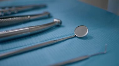Stomatolojide bilinmeyen bir diş hekimi tarafından çekilmiş yakın plan diş aynası. Temiz sağlık hizmetleri bürosunda sterilize edilmiş aletler. Diş hekimliği kliniğinde muayene ve tedavi için hazırlanmış profesyonel araçlar