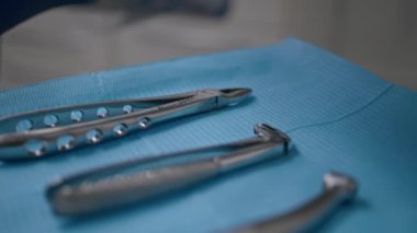 Mavi giysi modern kliniğinde sterilize edilmiş diş aletleri. Stomatolojide tedavi ve oral bakım için kullanılan profesyonel sağlık araçları. Diş hekimi işlemleri için dişçilik ekipmanları.