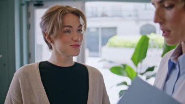 Klinikteki doktorla konuşan kız hasta. Yakın plan. Hastanedeki genç bayana orta yaşlı bir doktor tedavi planını açıklıyor. Genel pratisyen ziyaretçiye sağlık testi gösteriyor.