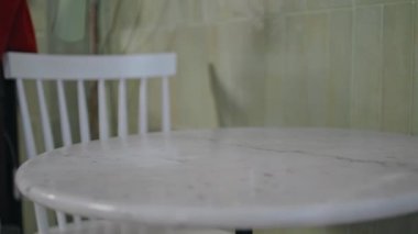 Garson elleri masa örtüsünü siliyor. Beyaz yüzey kafeteryasını ıslak bezle temizleyen kimliği belirsiz bir kadın işçi. Kadın, konukseverlik ortamında temizlik yapmaya çalışıyor..