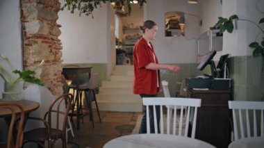 Restoran çalışanı boş salondaki dijital kasiyere dokunuyor. Çalışan kadın personel, müşteri ödemelerini profesyonelce yapıyor. Modern kafeterya servisi.