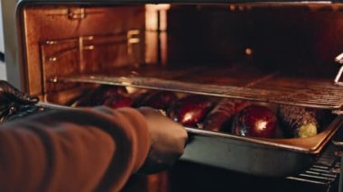 Mutfak işçisi patlıcan pişiriyor yakın çekim için fırına tepsi koyuyor. Bilinmeyen şef sıcak mutfak alanında sebze hazırlıyor. Yemek pişirme konusunda profesyonel. Kapalı alanda dikkatli.