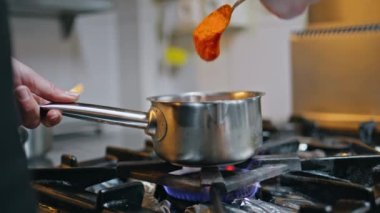 Mutfak ocağında kaşıkla sosu karıştıran eller yakın plan. Meçhul kadın şef fırında yemek için domates sosu pişiriyor. Mutfak işçisi modern mutfakta sağlıklı yemekler hazırlıyor..
