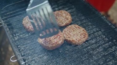 Orman pikniğinde mangal ızgarasında hamburger pişiren kimliği belirsiz bir adam. Tanınmayan bir tatilci, rahat atmosferde kömürlerin üzerinde taze et hazırlıyor. Bbq parti konsepti.