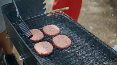 Hamburger köfteleri ızgarada ızgara yapıyor. Orman pikniğinde hamburgerlere et hazırlayan tanınmamış bir adam. Kömürde et pişiren genç insan gevşemiş bbq partisinin tadını çıkarıyor. Hafta sonu toplama kavramı.