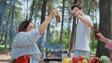 Mutlu arkadaşlar BBS 'in yakın çekiminde bira kızartıyorlar. Ormanda yaz pikniğinde içki içen gülümseyen gençler. Neşeli arkadaşlar doğada birlikte eğleniyorlar. Birlikte barbeküde yemek hazırlıyorlar..