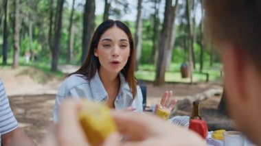 Güneşli bir piknik gününde arkadaşlarıyla iletişim kuran bir kadın. Hafta sonu Green Park 'ta aile üyeleriyle konuşurken mutlu esmer. Gülümseyen kız orman doğasının tadını çıkarıyor arkadaşlarıyla sosyalleşiyor.