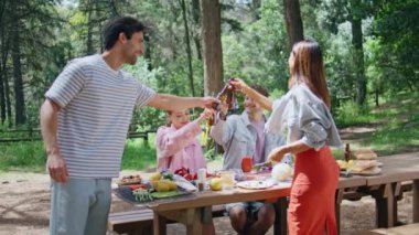 Neşeli gençler güneşli parktaki tasasız hafta sonu pikniğinde bira içiyorlar. Mutlu grup arkadaşları yaz toplantılarında şişelerle kadeh kaldırıyor. Gülümseyen insanlar güzel ormanda dostça buluşmanın keyfini çıkarıyorlar..