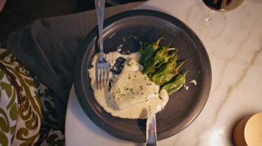 Siyah tabakta servis edilen yeşil biberli lüks restoran yemeği. Meçhul kadın eli kremalı soslu lezzetli sebzeleri alıp gurme yemeğinin tadını çıkarıyor. Kafeteryada güzel bir aşçılık sunumu.