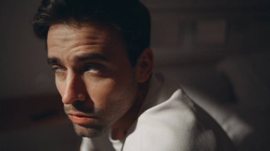 Düşünceli bir adam yatak odasında oturmuş, ay ışığına yakından bakıyor. Karanlık bir evde uyku sorunu yaşayan düşünceli bir adam. Tıraşsız, üzgün bir erkek, geceleri depresyonda..