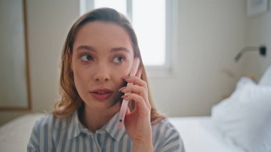 Cep telefonuyla konuşan bir kızın portresi rahat beyaz yatakta oturuyor. Güzel bir kadın hafta sonu samimi yatak odasında arkadaşlarını arıyor. Bayan, evde ciddi cep telefonu konuşmaları yapıyor..