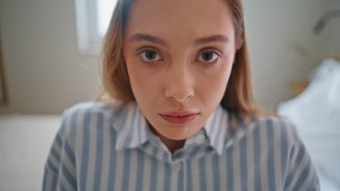 Aydınlık odanın iç kısımlarına yakından bakan kadın. Haftasonu beyaz yatak odasında oturan büyük güzel gözlü nazik bir kız. Çizgili pijamalı, yatakta dinlenen güzel bayan..