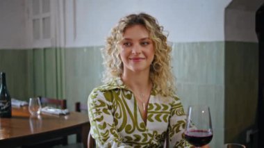 Restoranda elinde şarap kadehi tutan gülümseyen sarışın arkadaş. Mutlu kıvırcık kadın duygusal olarak en iyi arkadaşa konuşuyor rahatça eğleniyor. Kafeteryada muhabbet eden neşeli kız arkadaşlar..