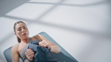 Spor salonundaki sıhhiye topuyla pres yapan kapanış sporcusu. Spor salonundaki kadın karın kaslarını tek başına çalıştırıyor. Karın egzersizi yapan kaslı kadın yerde ağır ekipmanlarla. 