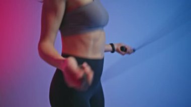 Boş neon oda kapanışında atlama halatıyla spor kadın vücudu antrenmanı yapıyor. Bilinmeyen bir kadın ip atlıyor. Beden eğitimi sırasında ekipman kullanan bayan sporcu kız.