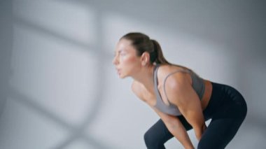 Spor salonunda halter kız kas antrenmanı. Güçlü kadın beyaz duvar arkasında metal ekipman tutarak vücut geliştirme egzersizinden zevk alıyor. Bayan vücut geliştirici içeride güç toplamak için egzersiz yapıyor. 