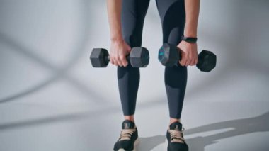 Spor salonunda dambıl egzersizi yapan spor eğitmeni vücudu. Anonim atletik kadın sırayla ağırlık egzersizleri yapıyor. Güçlü motivasyonlu bayan kaslarını içeride tek başına çalıştırıyor. Spor konsepti 