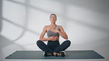 Lastik hasırın önünde Asana egzersizi yapan kızı içine çekiyor. Huzurlu kadın evde tek başına meditasyon yapıyor. Ruhani yoganın keyfini çıkaran genç bayan huzurlu bir sabahta dinleniyor. Akıl sağlığı konsepti 