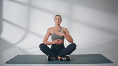 Yogi bayan lastik minder üzerinde nefes egzersizi yapıyor. Asana 'da meditasyon yapan sakin bir kadın, gözleri kapalı. Yoganın tadını huzur içinde çıkaran odaklanmış bir kız. Akıl sağlığı konsepti 