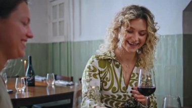 Şarap içen iki kadın samimi bir restoranda cep telefonu ekranına gülüyor. Mutlu kız arkadaşlar kadehlerini tokuşturarak günlük toplantılarda dostça sohbetin tadını çıkarıyorlar. Kadın arkadaşlığı kavramı.