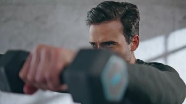 Kas sporcusu spor salonunda dambılları kaldırıyor. Hafif stüdyoda biseps egzersizi yapan bir sporcu. Sadece spor kulübünde ağırlık tutan konsantre bir esmer antrenör. 
