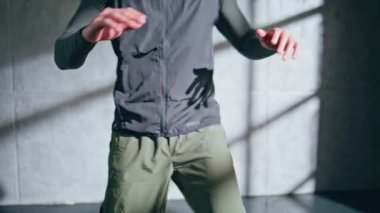 Yüksek diz egzersizi yapan bir sporcu. Bilinmeyen sporcu spor kıyafetlerine atlarken ısınıyor. Tanınmayan fitness elemanı çatı katında koşu antrenmanına hazırlanıyor. Eğlence sporları eğitmeni 