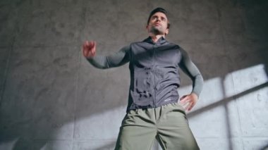 Jimnastik salonunun alt katında vücut esneme hareketleri yapan adam. Motive olmuş atletik bir adam sağlık eğitiminde çalışıyor. Spor giyinen erkek sporcu spor egzersizi hazırlıyor. Esmer formda antrenör kaslarını ısıtır.