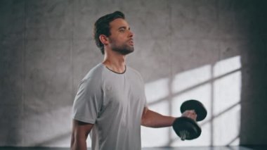 Çatı katındaki spor salonunda ağırlık kaldıran güçlü bir kaldırıcı. Güçlü bir adam halterle bisepsi pompalıyor. Spor kulübünde spor antrenmanında tek başına spor yapan bir sporcu. Etkin yaşam tarzı