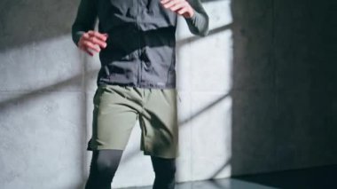 Çatı katında atlet bacakları antrenmanı. Profesyonel sporcu vücut egzersizi şortla diz egzersizi yapıyor. Tanınamayan güçlü erkek tek başına ısınıyor. Koşucu spor salonuna hazırlan. 