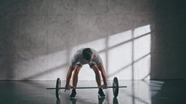 Spor salonunda kaslı sporcu ağırlık kaldırıyor. Halterle bisepsi pompalayan bir sporcu. Güç egzersizinden önce erkek güç toplayıcı ağır nefes alıyor. Güçlü adam spor yaparken konsantre olduğunu hissediyor. 