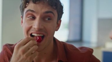 Neşeli bir adam mutlu bir ifadeyle kiraz yiyor kız arkadaşıyla yakın çekim yapıyor. Gülümseyen koca, kahvaltıda karısına böğürtlen yiyor. Rahatlamış adam, mutfakta güzel aile anlarının tadını çıkarıyor..