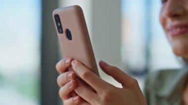 Modern bir dairede cep telefonuyla mesajlaşan bir kadın. Rahatlamış ev atmosferinde akıllı telefonlu sosyal medyaya göz atan gülümseyen kadın. Çekici esmer, kapalı alanda cep telefonuyla mesajlaşmaktan zevk alıyor..