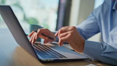 Uzaktan kumanda ofisindeki dizüstü bilgisayarda yazan profesyonel eller. Gülümseyen çevrimiçi işçiler, yoğun iş günlerinde bilgisayar ekranına bakarak projeden memnun kalıyorlar. Mavi tişörtlü mutlu adam dikkatle çalışıyor..