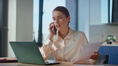Memnun olmayan bir kadın cep telefonuyla konuşuyor iş yerindeki belgeleri yakından inceliyor. Sinirli iş kadını laptoptan arıyor. Sinirli bayan yönetici akıllı telefon konuşmalarıyla tartışıyor. Stres altında..