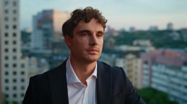 Alacakaranlık kapanışında çatıya bakan şık takım elbiseli adam. Ofis balkonunda kariyer yapmayı düşünen kendine güvenen bir iş adamı. Ciddi bir erkek işyeri sahibinin portresi kentsel manzaranın keyfini çıkarıyor