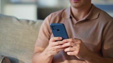 Hafta sonu ev hapsinde rahat koltukta cep telefonu tutan adam. Rahat bir adam cep telefonundan sosyal medya içeriğini izliyor. Evde kanepede dinleniyor. Sakin serbest çalışan akıllı telefon uygulamasını tarıyor.