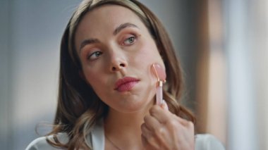 Sağlıklı cilt aynası yansıması için yeşim taşı kullanan güzel bir kadın. Kapalı çekim gülümseyen kız evde özen göstermekten zevk alıyor. Bayan kozmetik cilt bakımı. Yüz ve cilt bakımı