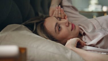 Sabah kızı, güneş ışığında gözlerini aç. Yakın plan. Huzurlu rahatsız kadın rahat bir yatakta akıllı telefon mesajlarıyla uyanıyor. Yorgun ve güzel bir model hafta sonu evde eğleniyor. Tembel tatil yaşam tarzı konsepti 