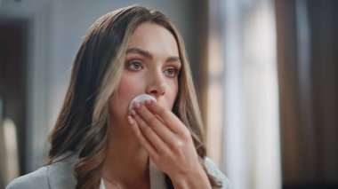 Işıl ışıl yüzlü, mutlu bir kadın. Hafif banyoda pamuk yastıkla kırmızı ruj sürüyor. Sakin, yetişkin bir kadın makyajın keyfini çıkarıyor içeride temizlik yapıyor. Yüz bakımı konsepti