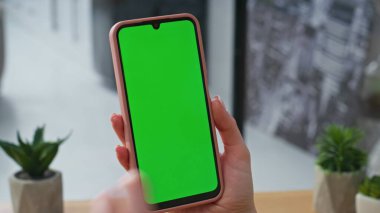 Modern işyerindeki akıllı telefonlara dokunan yönetici parmağı. İnternette cep telefonu kullanarak veri arayan kimliği belirsiz bir kadın. İş kadını kreatif ajansdaki yeşil ekran cep telefonunu dinliyor. 