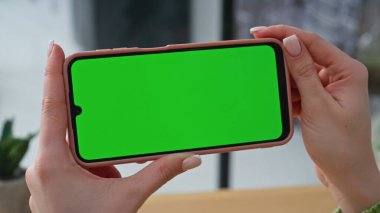 Şirketin iş yerinde el ele tutuşan yatay model cep telefonu. Bilinmeyen kadın uzaktan kumandalı ofisteki yeşil ekran akıllı telefona bakıyor. İş kadını dairede cep telefonuyla konuşuyor.