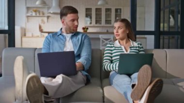Ev sevdalıları yumuşak kanepe yerinde dizüstü bilgisayarlara göz atıyorlar. Mutlu adam pozitif kadın klavyesini yazarken gülümseyerek birbirine bakıyor. Apartman dairesinde birlikte çalışan genç çift. 